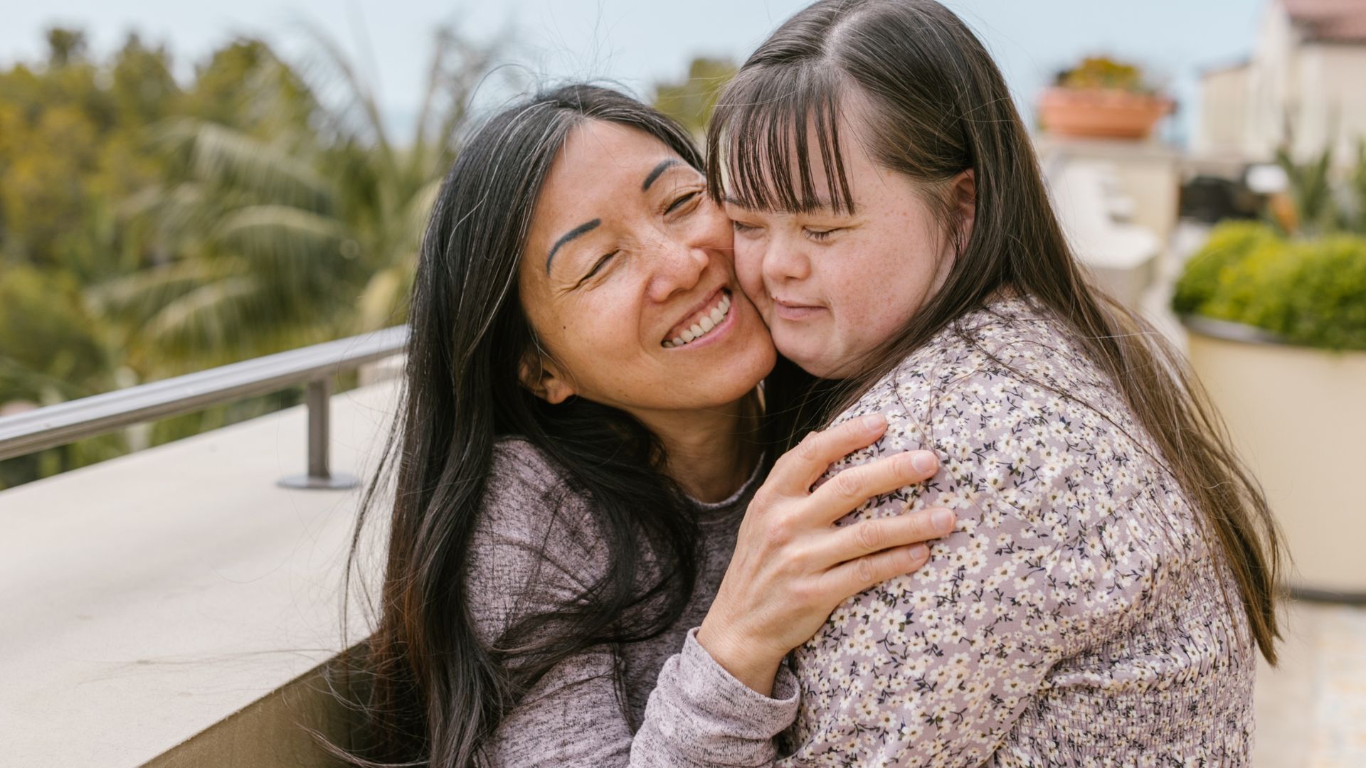 Two women smiling and hugging outdoors.