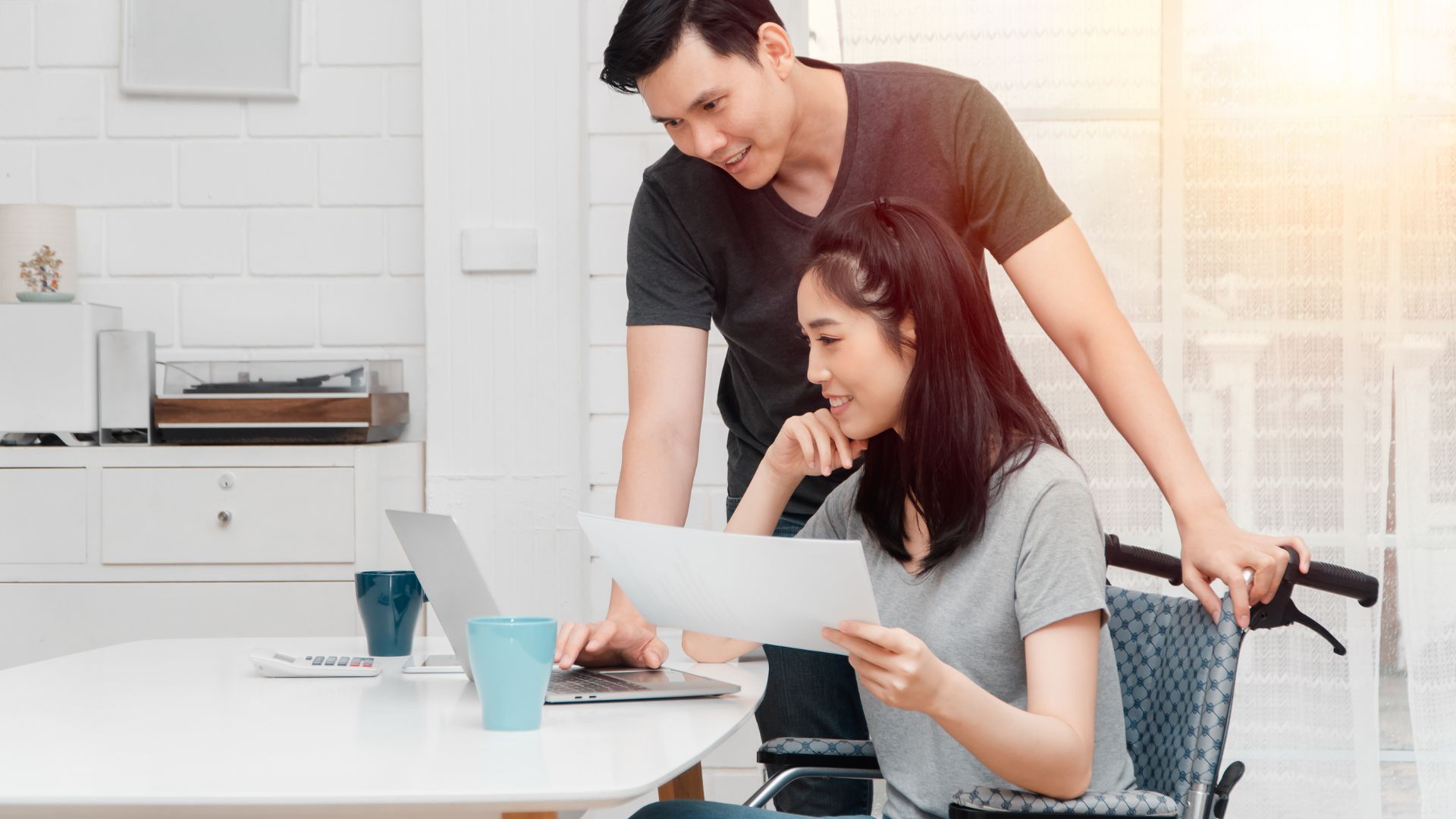 Man helping woman in wheelchair with paperwork.